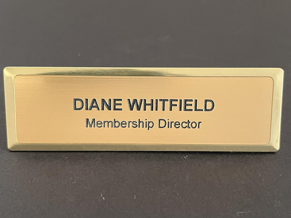 A name badge on a gold metal bar with a brushed metal-look face. The text DIANE WHITFIELD is engraved in a bold, dark sans-serif font, with the title Membership Director in a smaller, standard font below.