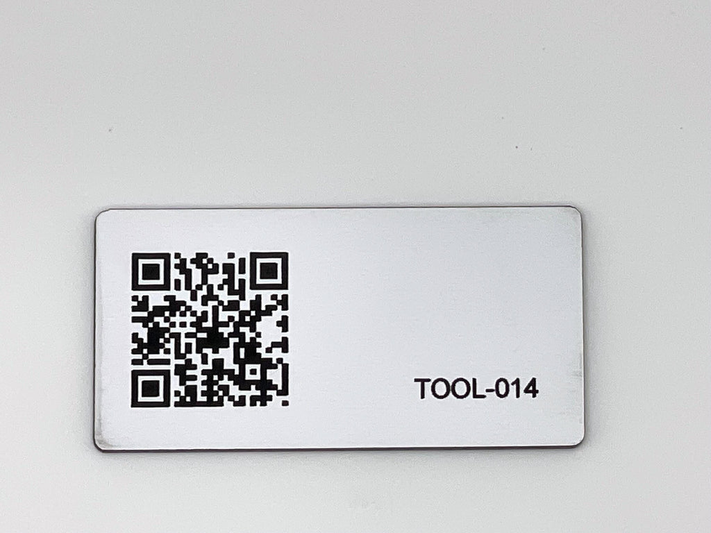 A rectangular white engraved tag featuring a black QR code on the left side and the text TOOL-014 in black on the right side. The tag has rounded corners and a smooth finish.