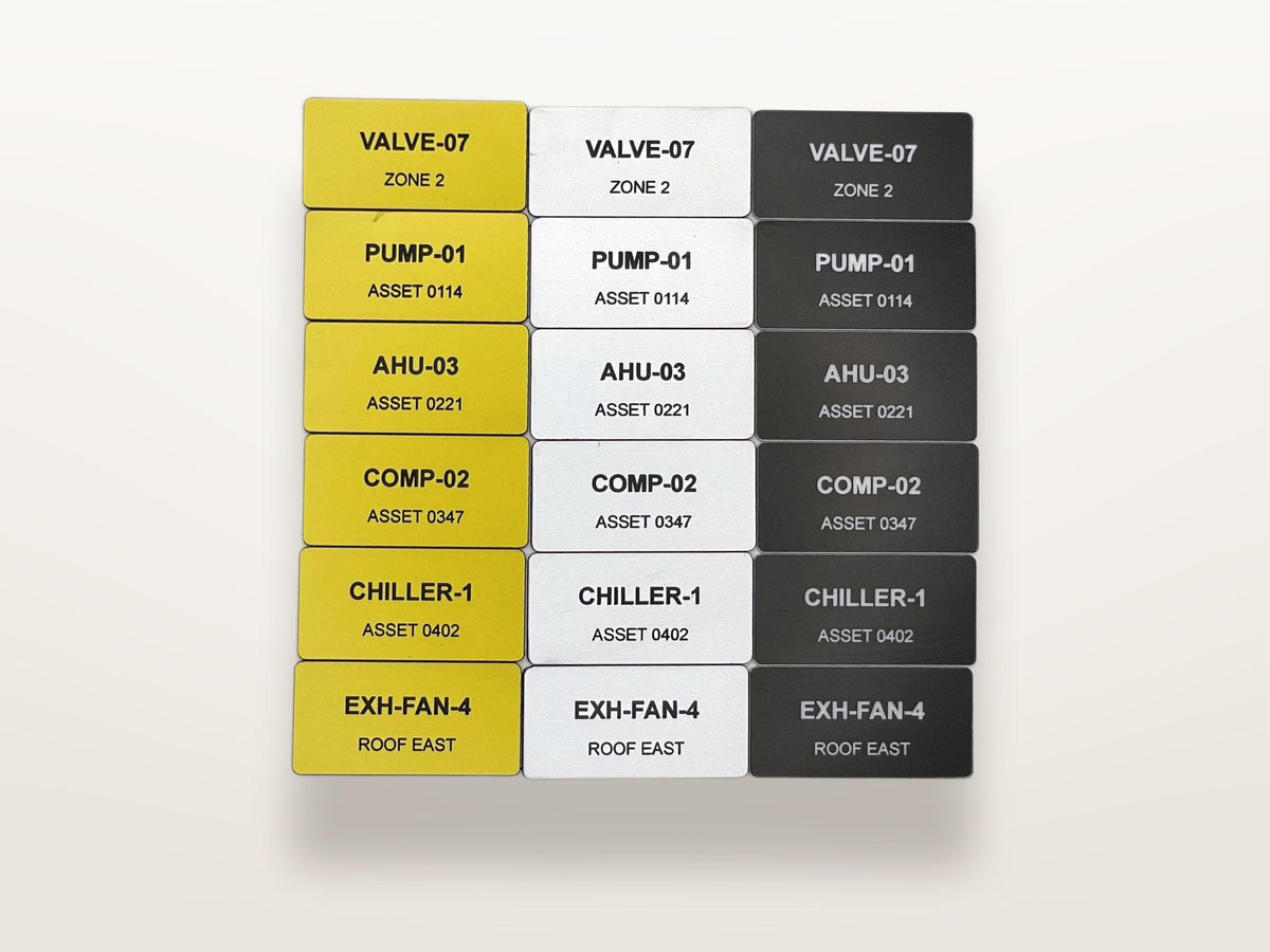 A grid of eighteen rectangular industrial labels arranged in three columns of yellow, white, and black. Each label features black text identifying equipment such as VALVE-07, PUMP-01, AHU-03, COMP-02, CHILLER-1, and EXH-FAN-4 with specific asset codes.