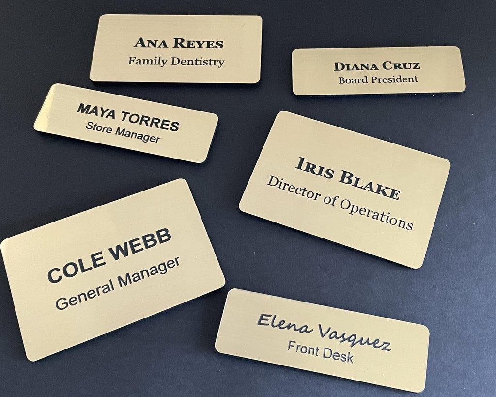 Six rectangular gold-toned name badges with black text. Names include Ana Reyes, Diana Cruz, Maya Torres, Iris Blake, Cole Webb, and Elena Vasquez, with titles below.