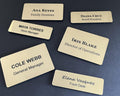 Six rectangular gold-toned name badges with black text. Names include Ana Reyes, Diana Cruz, Maya Torres, Iris Blake, Cole Webb, and Elena Vasquez, with titles below.