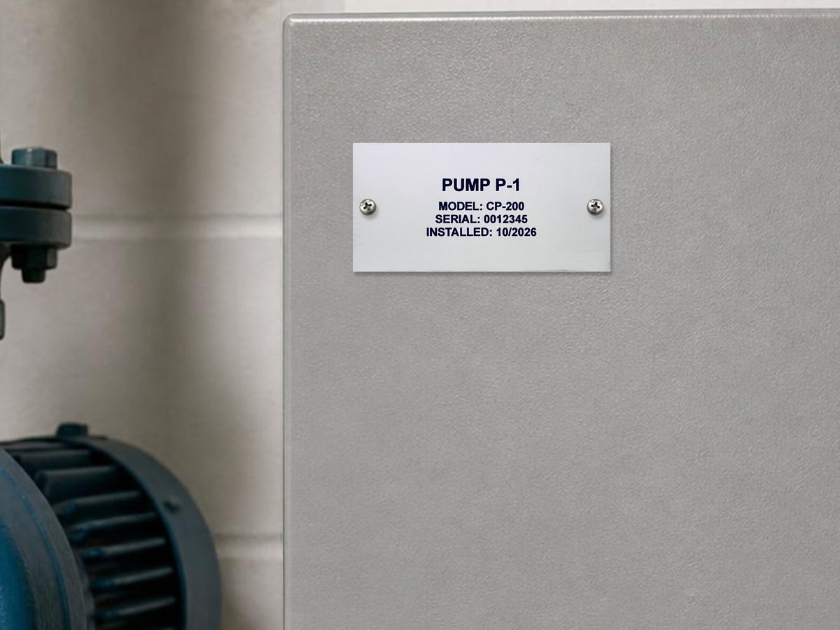 White engraved data plate reading PUMP P-1, MODEL: CP-200, SERIAL: 0012345, INSTALLED: 10/2026, screwed to a pump's gray control box.