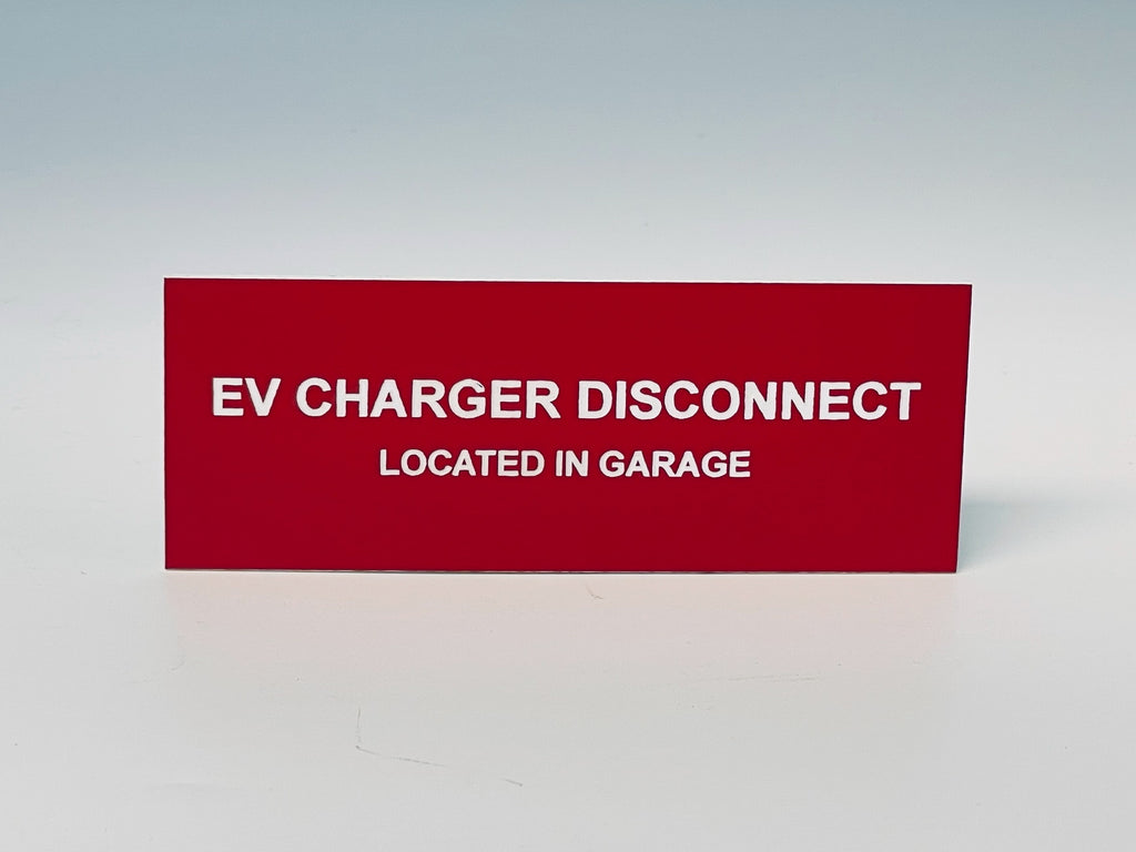 Red engraved label with white letters reading EV CHARGER DISCONNECT, LOCATED IN GARAGE.