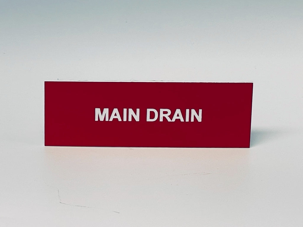 Red engraved placard with white letters reading MAIN DRAIN.