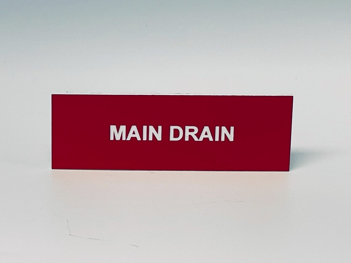 Red engraved placard with white letters reading MAIN DRAIN.