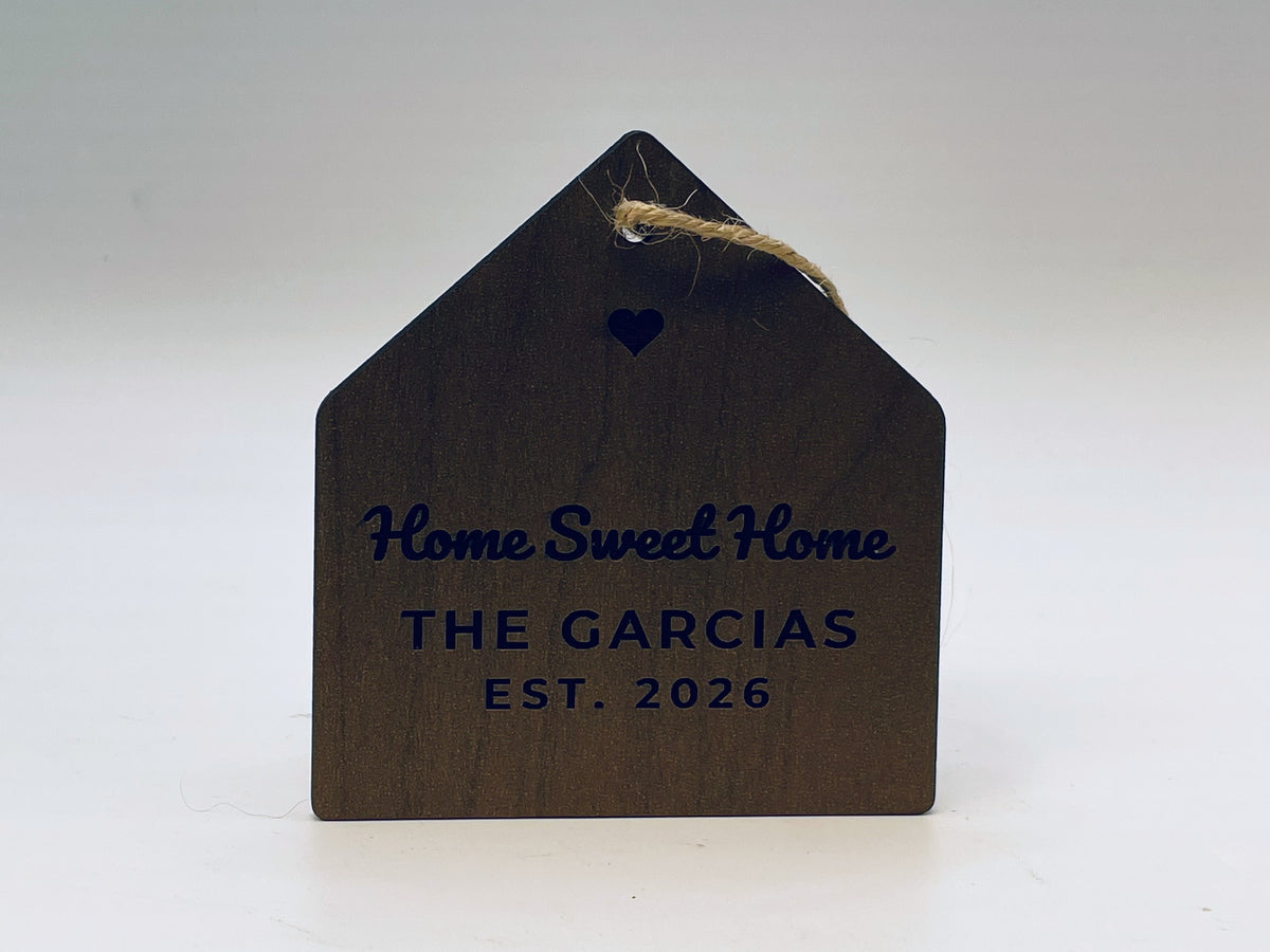House-shaped ornament in a walnut finish on jute twine: a cut-out heart, Home Sweet Home, THE GARCIAS and EST. 2026.