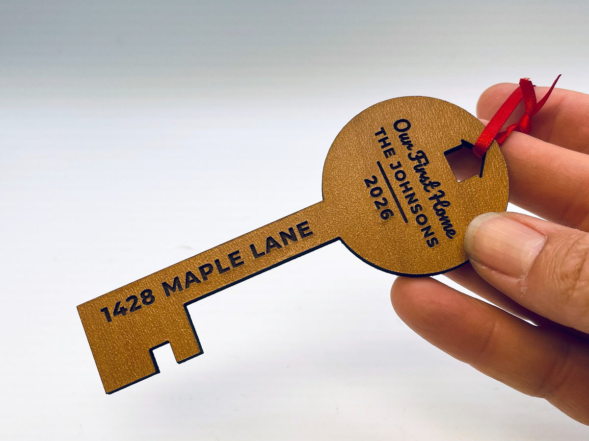 A hand holding the key ornament in a cherry finish, for size: about 4.6 inches long.