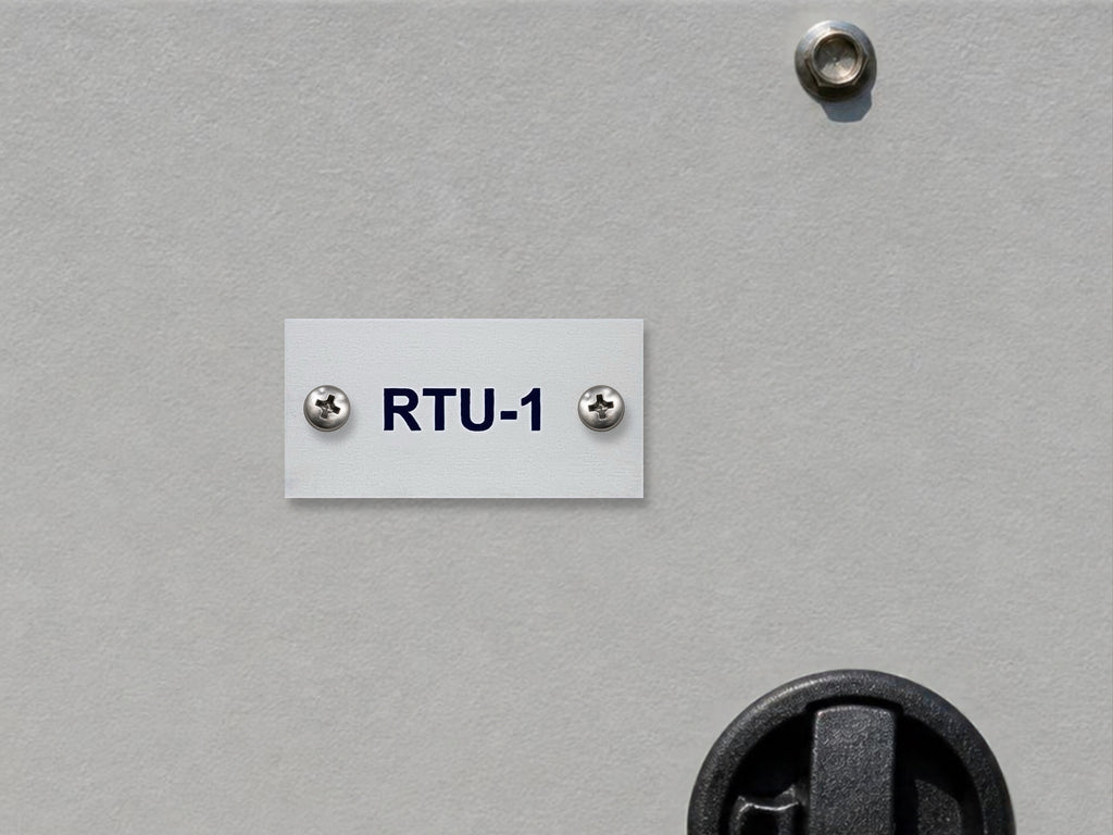 White engraved RTU-1 tag with black letters, screwed to the gray access panel of a rooftop HVAC unit near its latch.