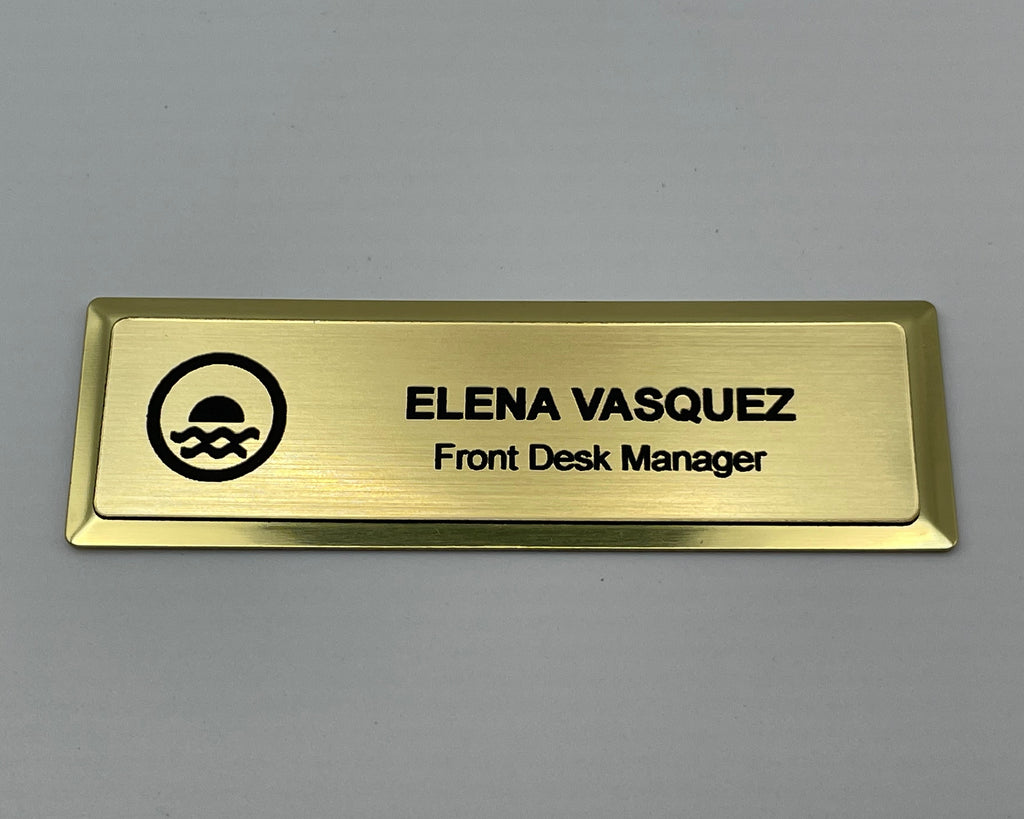 Gold metal bar name badge with an engraved logo, ELENA VASQUEZ, Front Desk Manager.