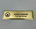 Gold metal bar name badge with an engraved logo, ELENA VASQUEZ, Front Desk Manager.