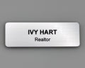 A rectangular silver name badge with a brushed metal-look finish. The text IVY HART is engraved in bold black capital letters on the top line, with the word Realtor in smaller black letters below.