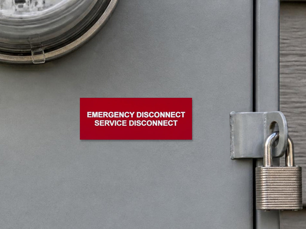 Red EMERGENCY DISCONNECT, SERVICE DISCONNECT label with white engraved letters on a gray meter main panel door beside the padlocked latch.