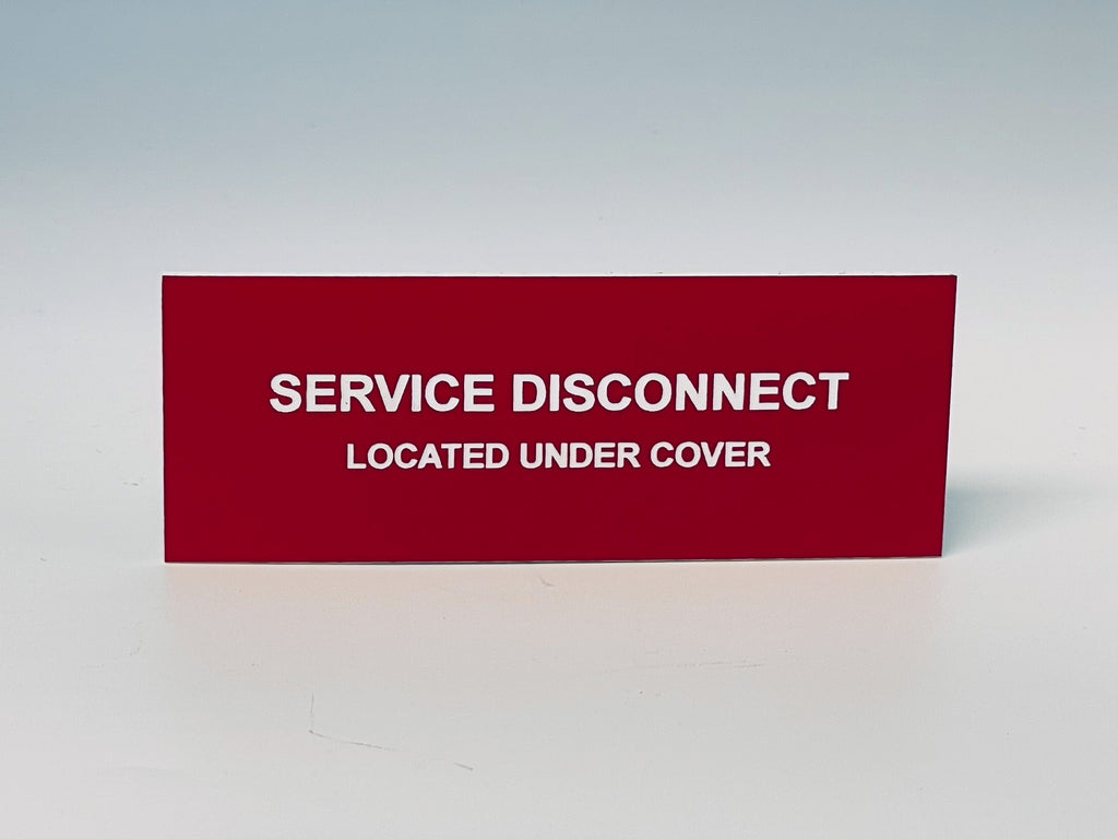 Red engraved label with white letters reading SERVICE DISCONNECT, LOCATED UNDER COVER.
