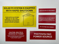 Solar PV label set: a yellow rapid shutdown placard with red photovoltaic disconnect, caution and power source labels.