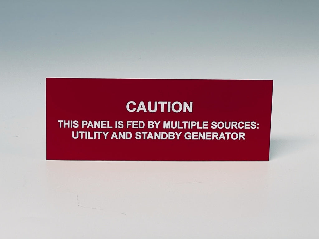Red engraved label with white letters reading CAUTION, THIS PANEL IS FED BY MULTIPLE SOURCES: UTILITY AND STANDBY GENERATOR.