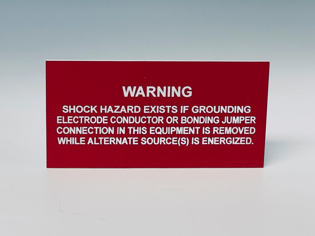 Red engraved label with white letters reading WARNING, SHOCK HAZARD EXISTS IF GROUNDING ELECTRODE CONDUCTOR OR BONDING JUMPER CONNECTION IN THIS EQUIPMENT IS REMOVED WHILE ALTERNATE SOURCE(S) IS ENERGIZED.