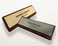 Two desk nameplates on dark walnut bases. One features a gold-toned metal-look plate engraved with VERONICA SANDOVAL Board President, the other a silver-toned plate with SARAH MITCHELL Store Manager.